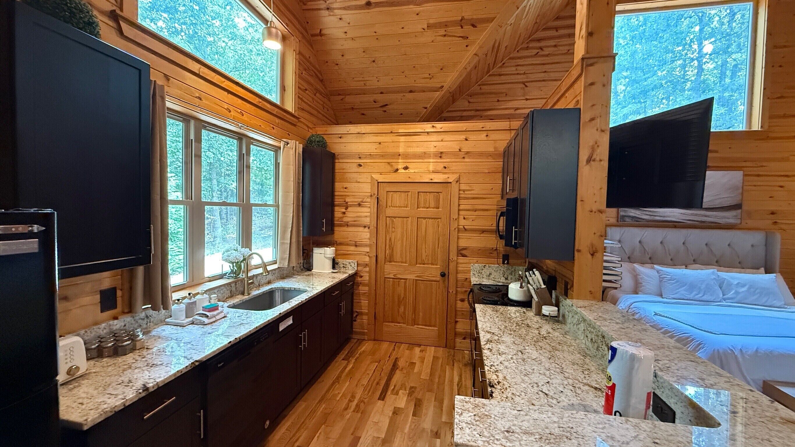 A compact log cabin interior with a kitchen, a dining area, and a bedroom.