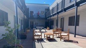 A courtyard with outdoor seating, potted plants, and a building with a balcony. - One block walk to gondola, ski lockers downstairs, River Trail close by! (Telluride)