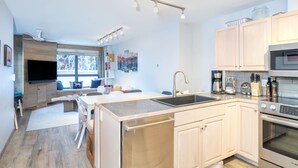 A modern kitchen with a central island, built-in appliances, and a dining area with a view. - One block walk to gondola, ski lockers downstairs, River Trail close by! (Telluride)