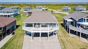 Et kystnært boligområde med flere huse med altaner og et centralt hus med en stor terrasse.