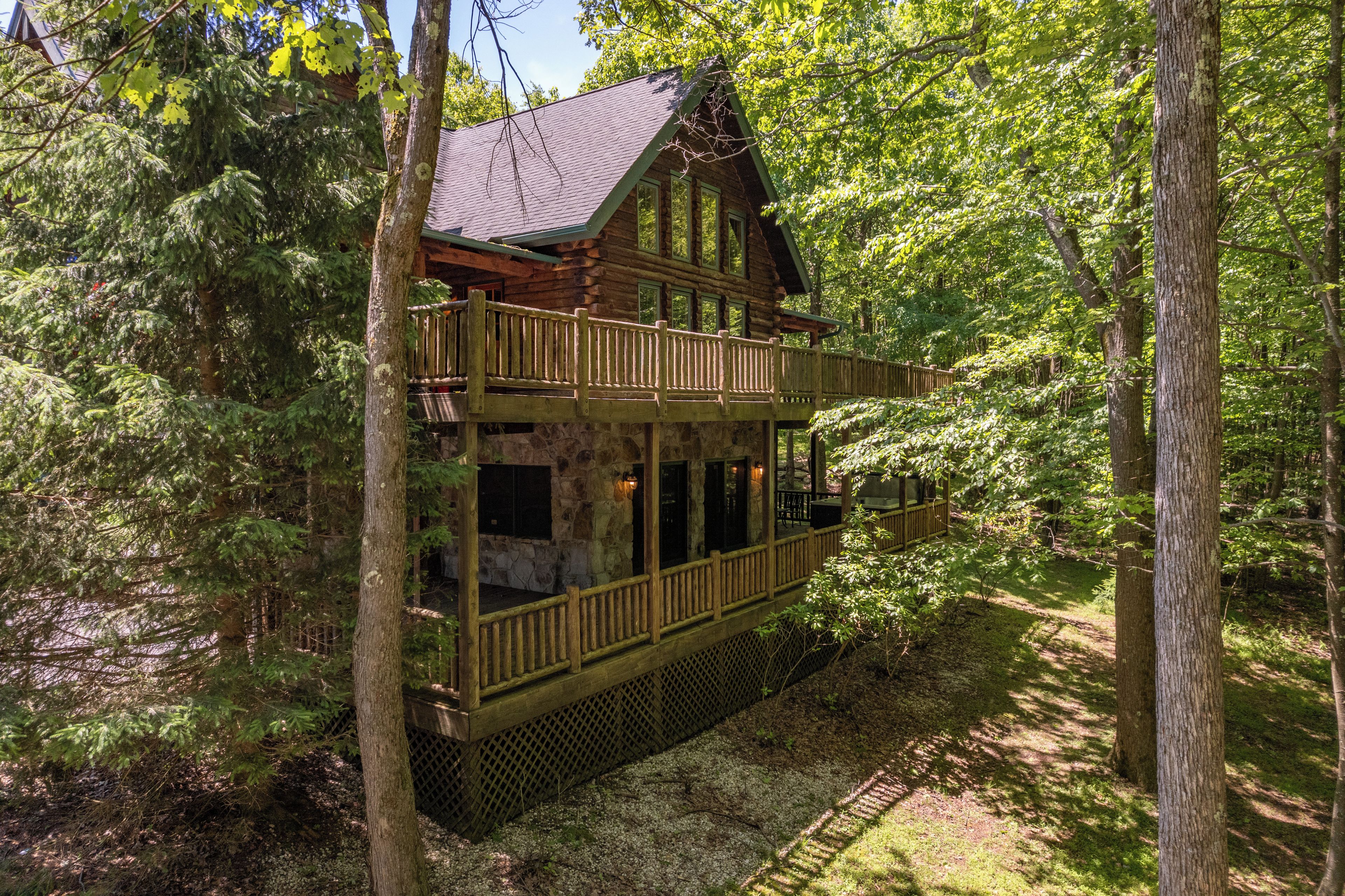 A log cabin with a balcony, surrounded by trees.