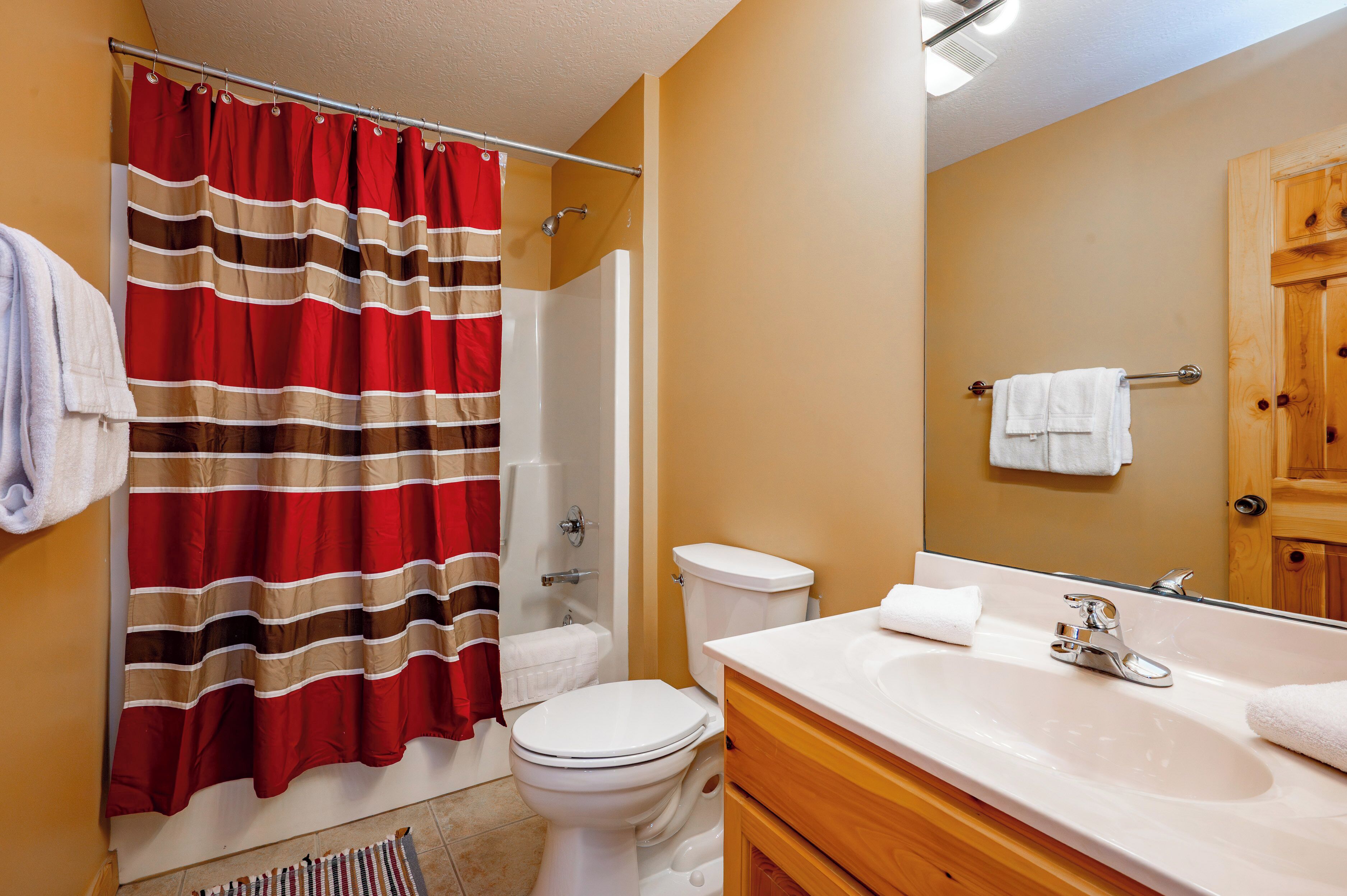 Ein Badezimmer mit Dusche, Toilette, Waschbecken und Spiegel.