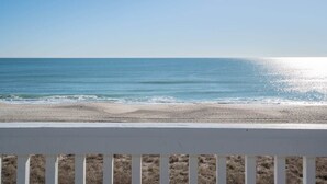 Uitzicht op een strand met een witte railing op de voorgrond.