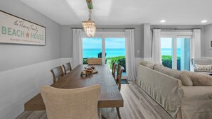 A dining area with a view of the ocean, a beach-themed sign, and a cozy seating area. - Gulf-Front, Remodeled Unit w/ Incredible Views + Free Attraction Tickets! (Seacrest)