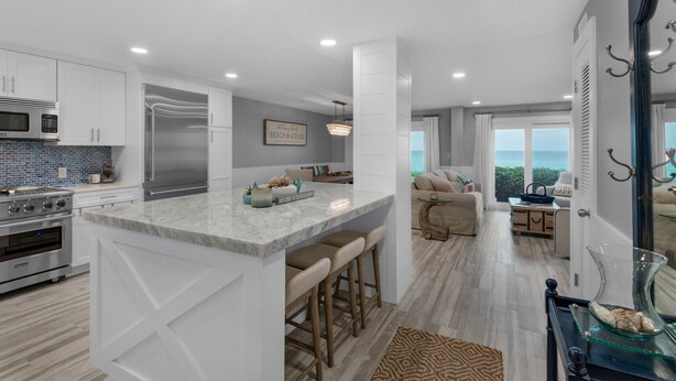 A modern kitchen with white cabinetry, a large island, and a view to the ocean. - Gulf-Front, Remodeled Unit w/ Incredible Views + Free Attraction Tickets! (Seacrest)