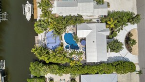 Une propriété résidentielle dotée d’une piscine, d’un quai pour bateaux et d’un aménagement paysager luxuriant.