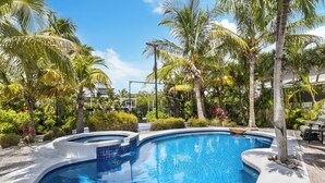 Une piscine entourée de palmiers et d’une végétation luxuriante.