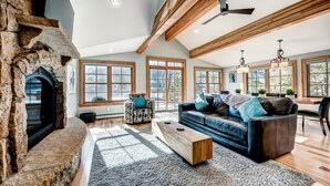 A spacious living room with a stone fireplace, large windows, and a high ceiling with exposed beams. - Beautiful new 4 bed/4bath private home, 4 blocks off Main St with all the amenities!! (Frisco)