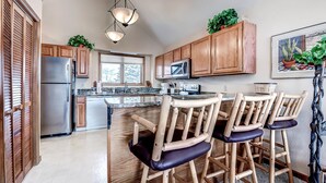 A modern kitchen with wooden cabinets, stainless steel appliances, and a central island with bar stools. - Comfortable and nice condo located a few blocks from Main Street, Frisco. Private Hot Tub! (Frisco)