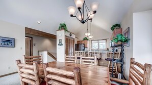 A dining area with a wooden table and chairs, a chandelier, and a kitchen in the background. - Comfortable and nice condo located a few blocks from Main Street, Frisco. Private Hot Tub! (Frisco)
