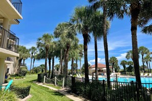 A resort with a pool, palm trees, and a clear blue sky. - FREE DAILY ACTIVITIES and listen to the sounds of the ocean from this gorgeous sunlit upgraded unit! (Saint Augustine)