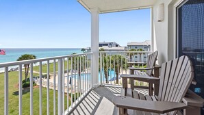 A balcony with a view of the ocean, a pool, and a flag.