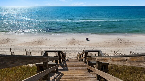 A wooden boardwalk leading to a beach with a wheelchair accessible path.