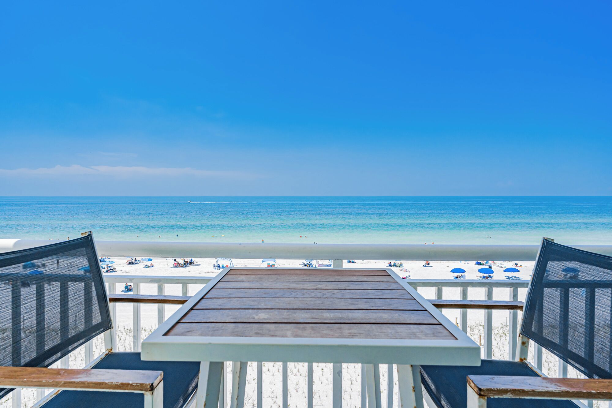 A wooden deck with a view of a beach and ocean.