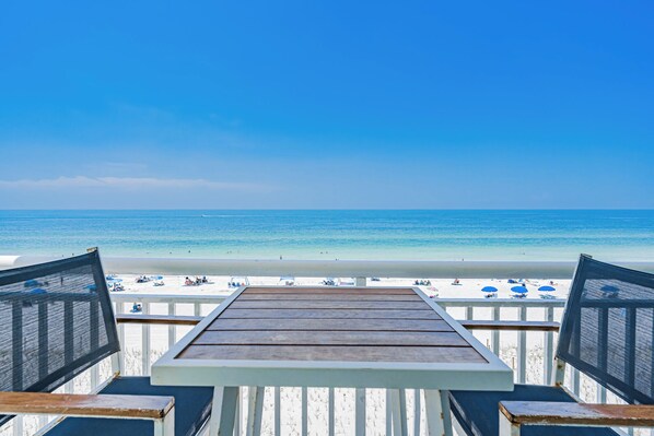 A wooden deck with a view of a beach and ocean.
