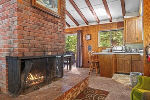A cozy interior with a brick fireplace, wooden cabinets, and a dining area. - Large Deck, Bunk Room, Garage, Close to Waterman's Landing "Agate Bay Ranch" (Carnelian Bay)