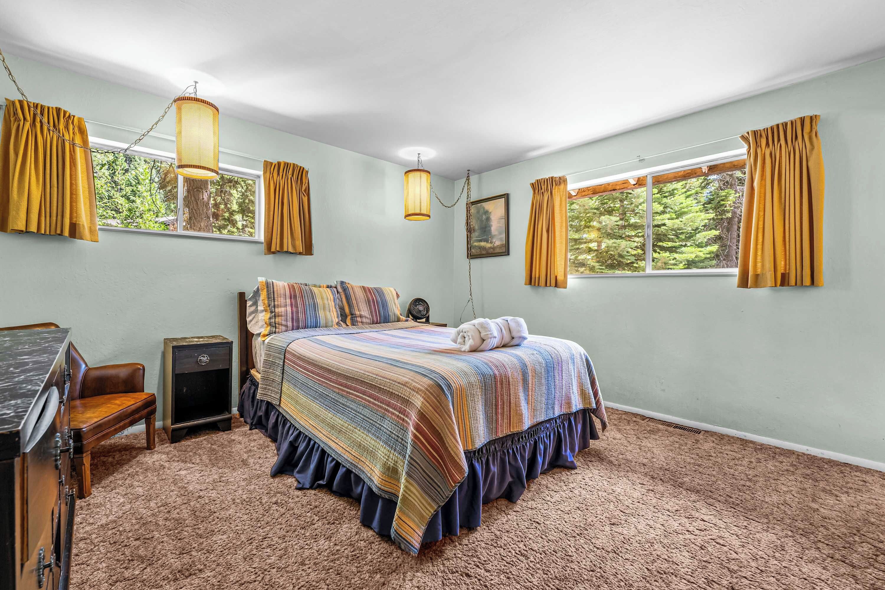 Ein Schlafzimmer mit Bett, Schreibtisch, Stuhl und einem Fenster mit Vorhängen.