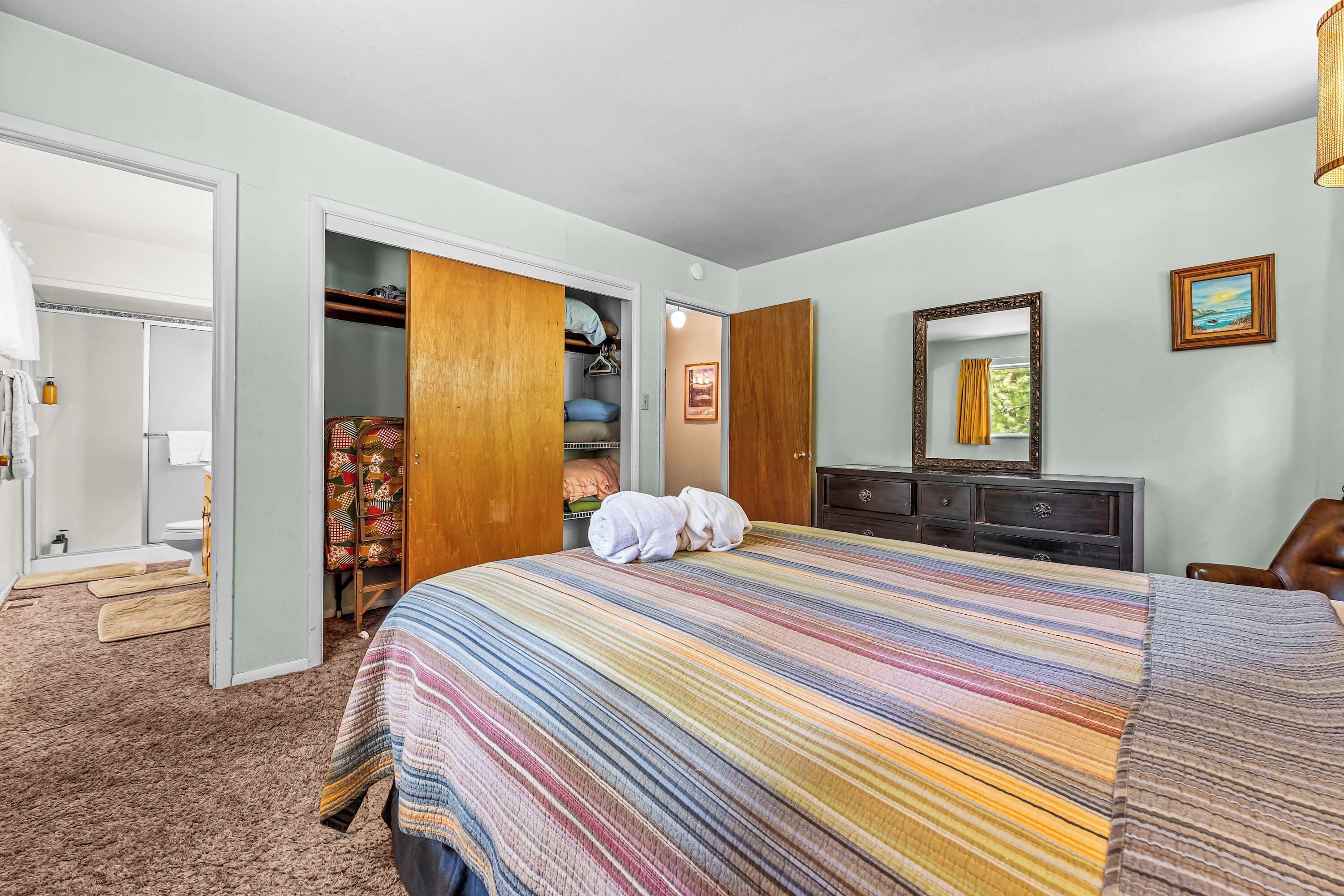 A hotel room with a large bed, a wardrobe, a mirror, and a dresser.