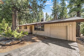 A single-story wooden cabin with a garage, surrounded by dense forest. - Large Deck, Bunk Room, Garage, Close to Waterman's Landing "Agate Bay Ranch" (Carnelian Bay)