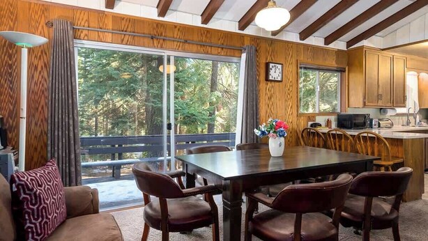 Un comedor con una mesa de madera, sillas y vistas al exterior.