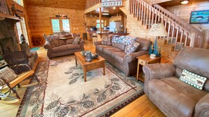 A cabin interior with a wooden interior, a staircase, a living room with two sofas, a coffee table, and a fireplace. - Sunset Ridge - New Hot Tub! Log Cabin, Views, Deck, Trails (Ferguson)