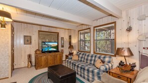 A cozy living room with a television, sofa, and ottoman. - Whispering Bear Lodge by Destination Big Bear : Pool Table! Foosball! Views! Internet! Deck! (Big Bear City)