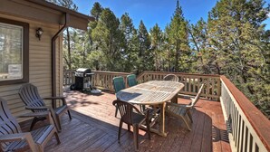A wooden deck with a table and chairs, a grill, and a view of trees. - Whispering Bear Lodge by Destination Big Bear : Pool Table! Foosball! Views! Internet! Deck! (Big Bear City)