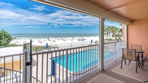 A balcony with a view of a beach and a swimming pool.