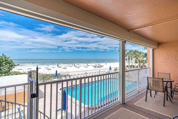 A balcony with a view of a beach and a swimming pool.
