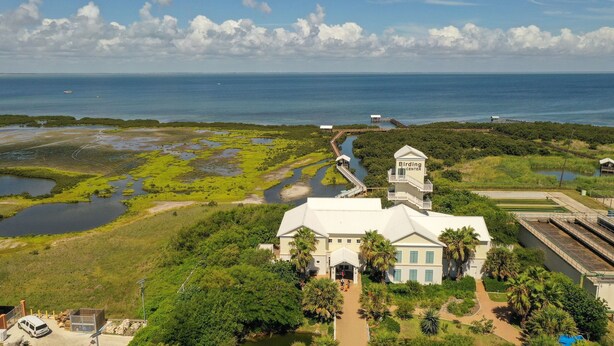A large building with a tower labeled "Birding Center," surrounded by lush greenery and a waterway. - Florence I 706 - Bargain beachfront vacay;Shining pool;Prime locale (South Padre Island)