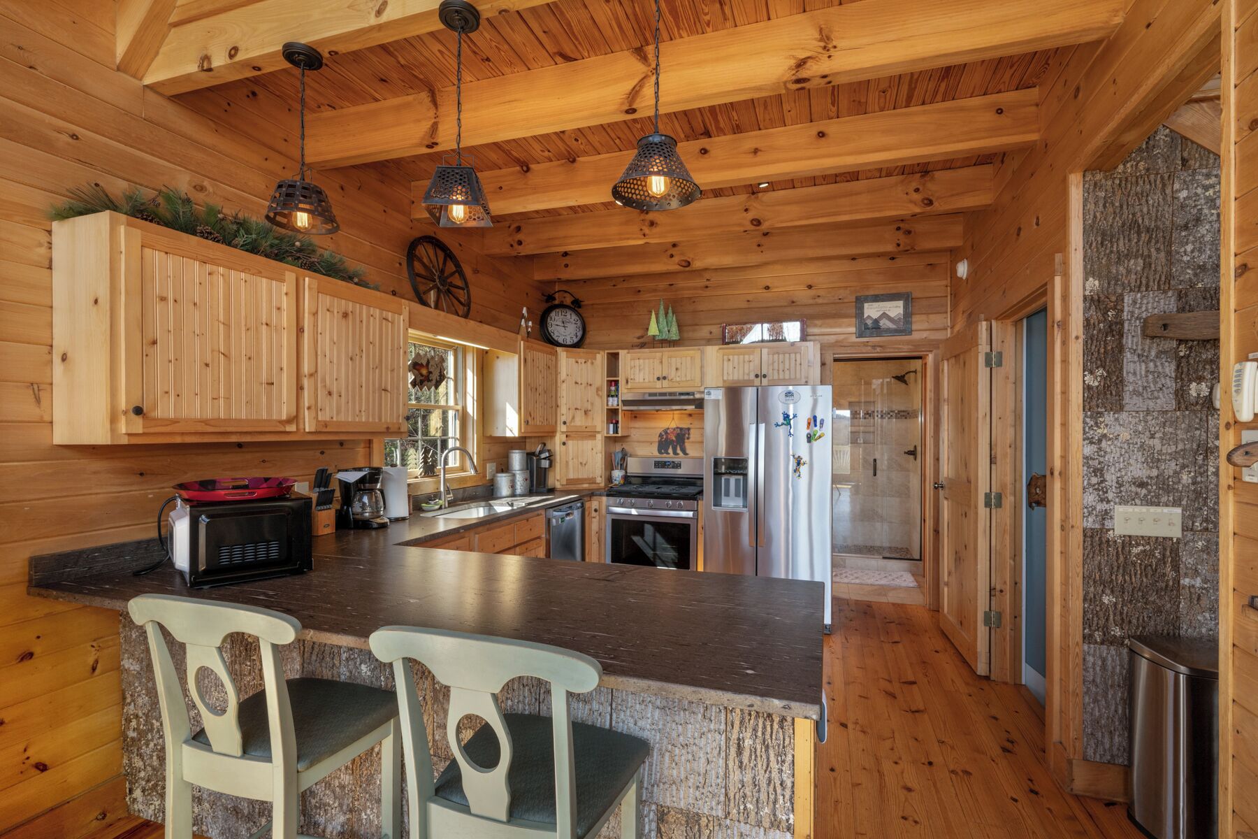 Una cocina tipo cabaña de madera con una isla central, armarios de madera y una pared de acento de piedra.