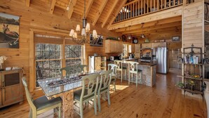 A spacious wooden cabin with a dining area, kitchen, and upper deck.