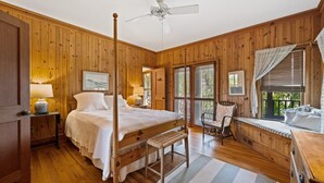 A wooden-paneled bedroom with a four-poster bed, a sitting area with a bench, and a window with blinds. - Natural and Serene Home Away from Home (Georgetown)