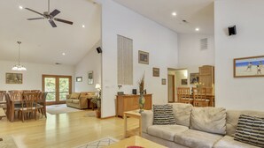 Un'ampia zona giorno con soffitto alto, una ventola a soffitto, un tavolo da pranzo con sedie, un divano e un tavolino da caffè.