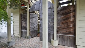 Un cancello di legno con un cartello ‘No Trespassing’, un vialetto in mattoni e un edificio con un'ampia porta garage.