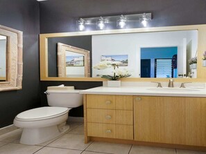 Une salle de bain comprenant des toilettes, un lavabo avec un miroir au-dessus et un meuble en dessous.