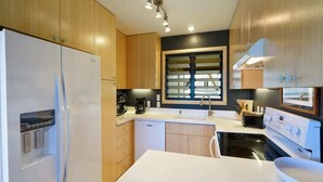 Eine moderne Küche mit Holzausstattung, einem weißen Kühlschrank, einer Spüle und einem Herd.