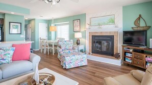 A living room with a fireplace, a television, and a dining area.