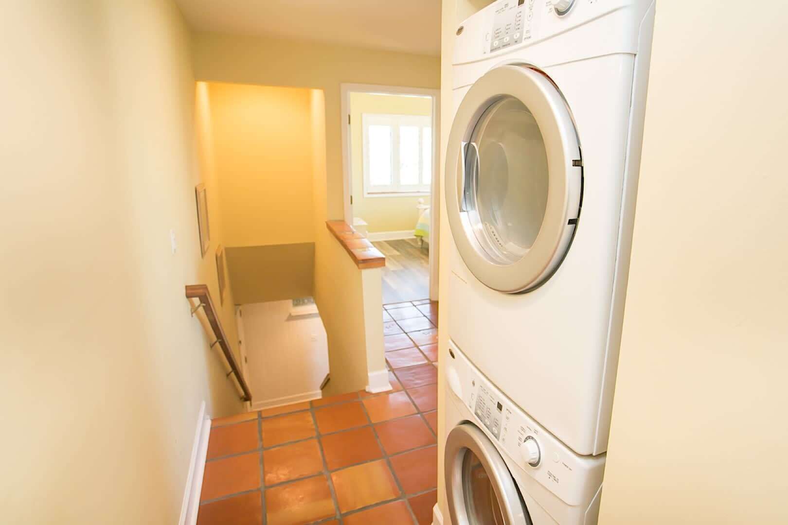 A laundry room with a washing machine and dryer, a white toilet, and a tiled floor.
