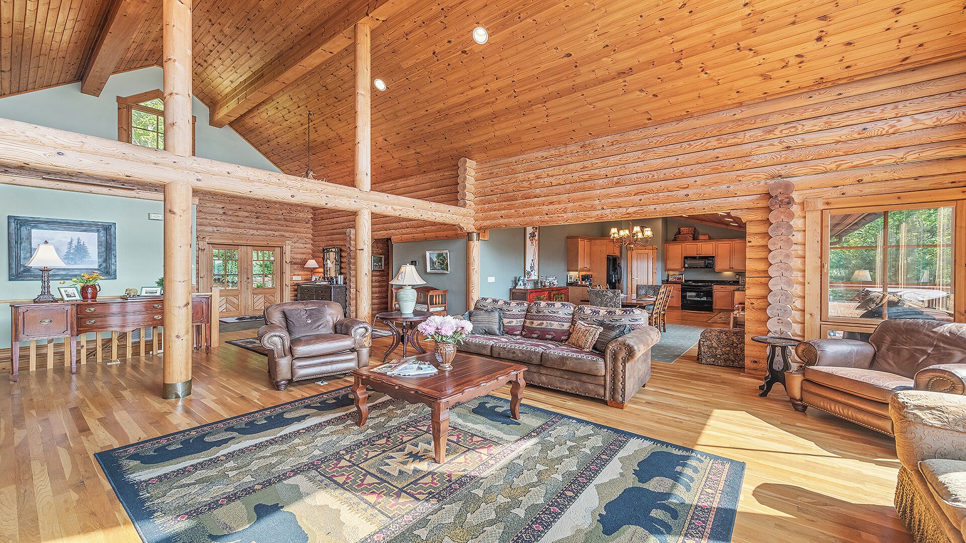 A spacious log cabin interior with a large living area, wooden floors, and a cozy fireplace.