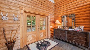 L’intérieur d’une cabane en rondins, avec une porte en bois, une commode avec un miroir et un tapis sur le sol.