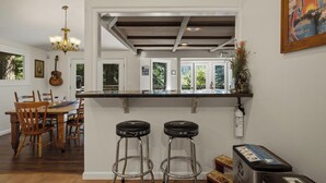 Una cocina con barra, sillas de madera, un candelabro y una guitarra en la pared.