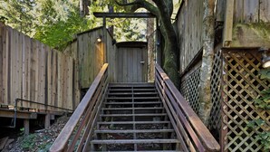 Una escalera de madera que conduce a una puerta, rodeada de vallas y paneles de celosía de madera.