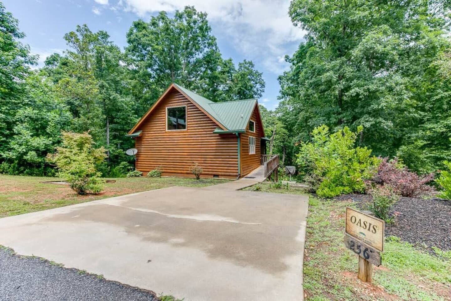 A log cabin with a green roof, surrounded by lush greenery and a clear sky.