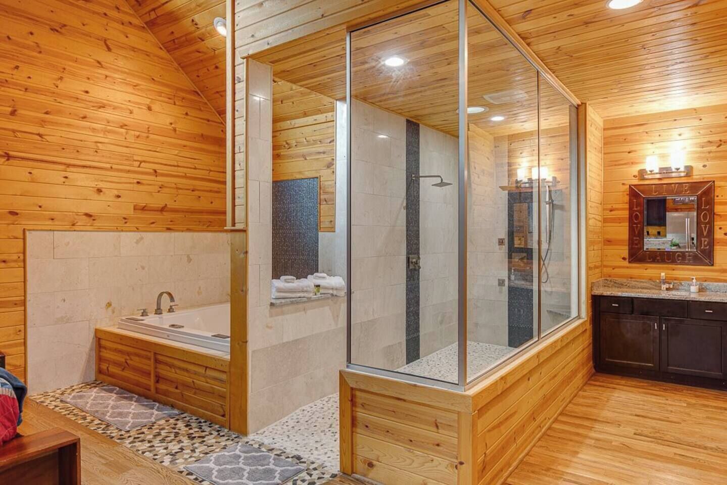 Une salle de bain moderne dotée d’une douche à parois de verre, d’une baignoire et d’un meuble-lavabo avec un miroir.