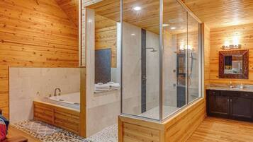 Une salle de bain moderne dotée d’une douche à parois de verre, d’une baignoire et d’un meuble-lavabo avec un miroir.