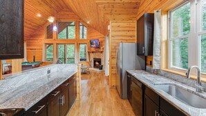 A log cabin interior with a kitchen, dining area, and fireplace. - Oasis- Spa Cabin W/Sauna, Jacuzzi, and Rain Shower/hot tub (Cleveland)