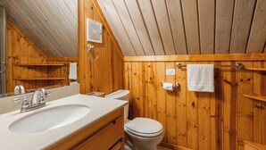 A wooden bathroom with a sink, toilet, and towel rack.