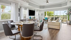 A spacious living room with a modern chandelier, a flat-screen TV, and a comfortable seating area. - Condo with Golf Course Views, Near Attractions (Kissimmee Fl)