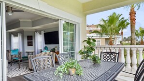 A balcony with a table and chairs, a potted plant, and a view of palm trees and buildings. - Condo with Golf Course Views, Near Attractions (Kissimmee Fl)